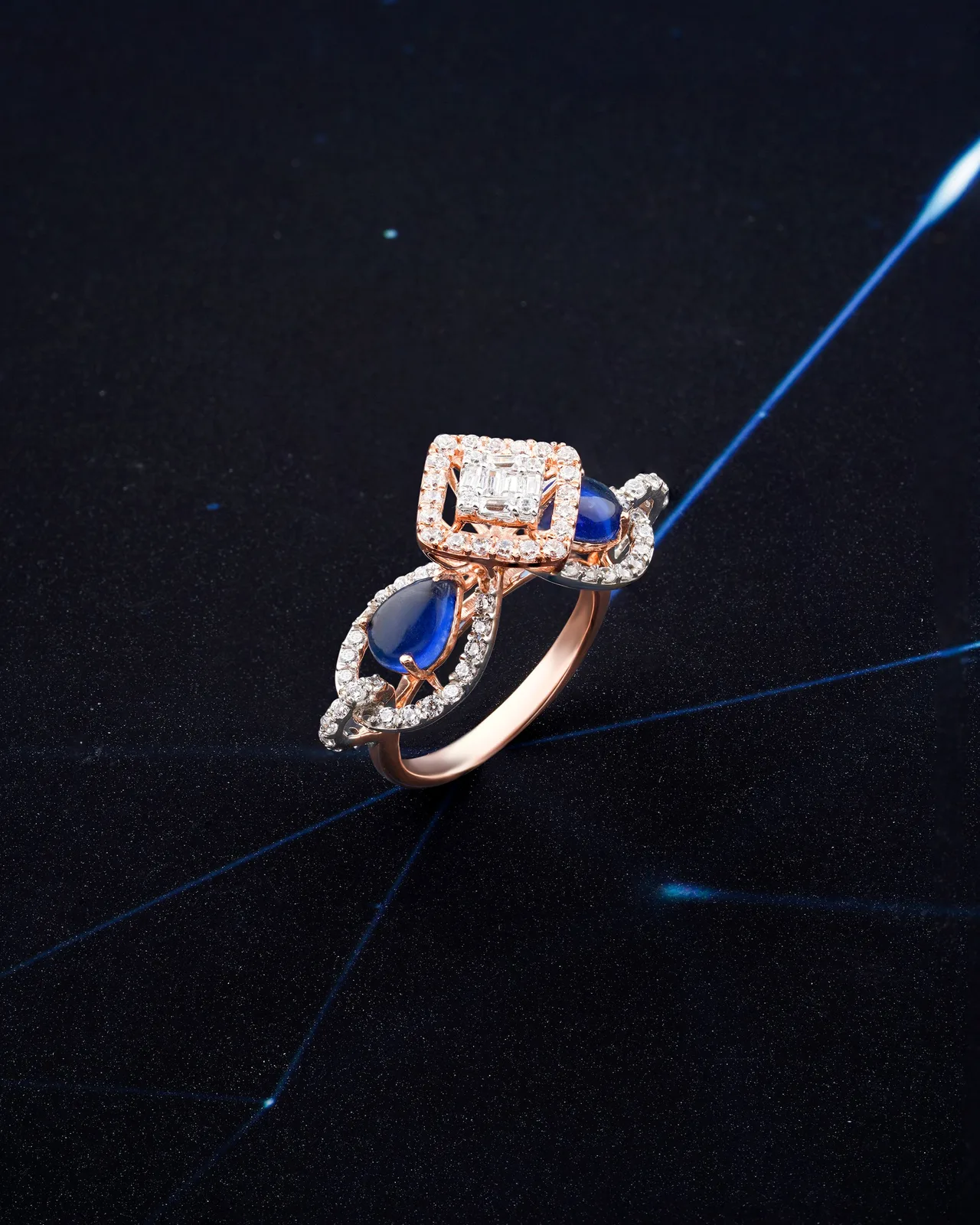 A gold ring set with sapphires and diamonds, on dark blue